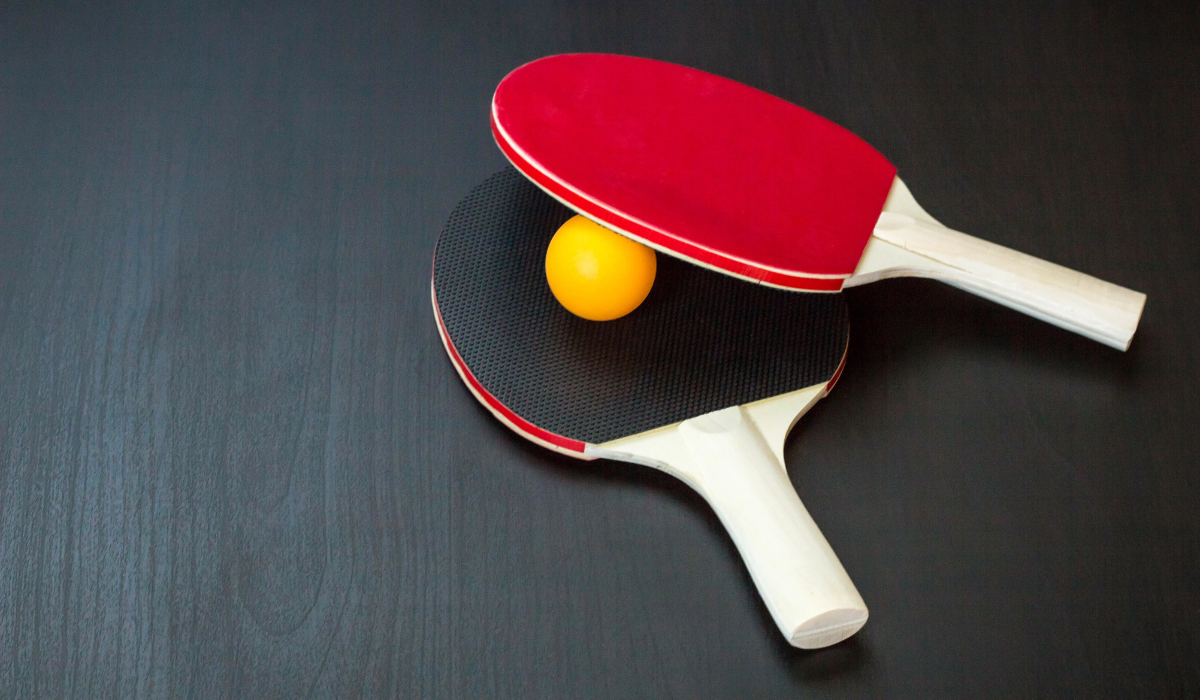 Table tennis black and red rackets with yellow ball on black background