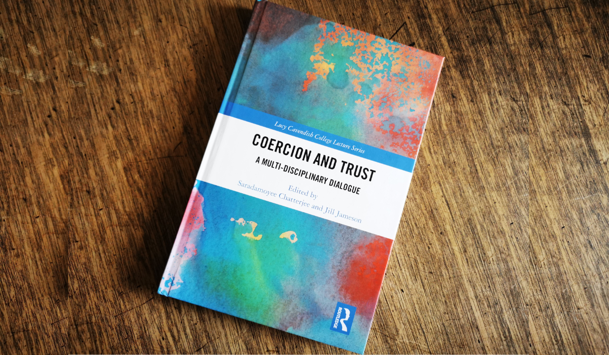 Coercion and Trust book (colourful cover) on wooden table