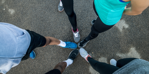 Aerial-like shot of five people in a circle joining feet