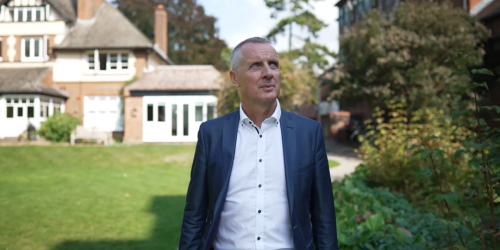 Gordon in the Lucy Cavendish gardens. He is wearing a blue suit jacket and white shirt