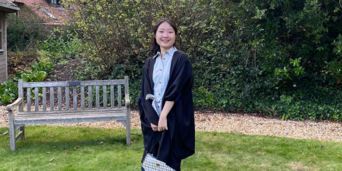 Wendy Chang wearing matricualtion gown posing on Strathaird lawn