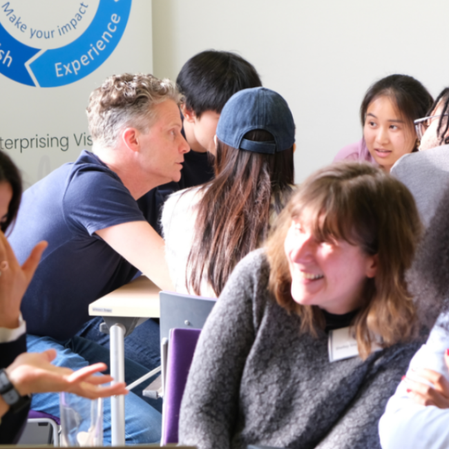 Mentor and students around table talking and smiling