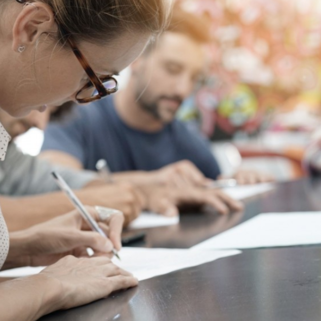 Woman writing on piece of paper at a table